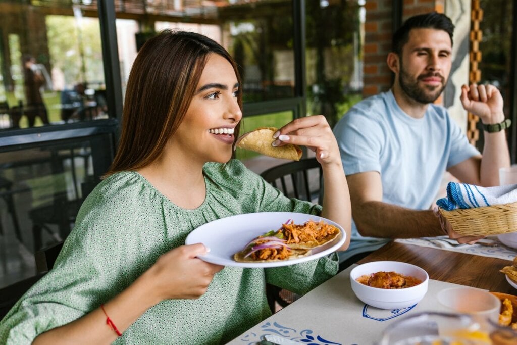 Mulher de blusa verde sentada comendo