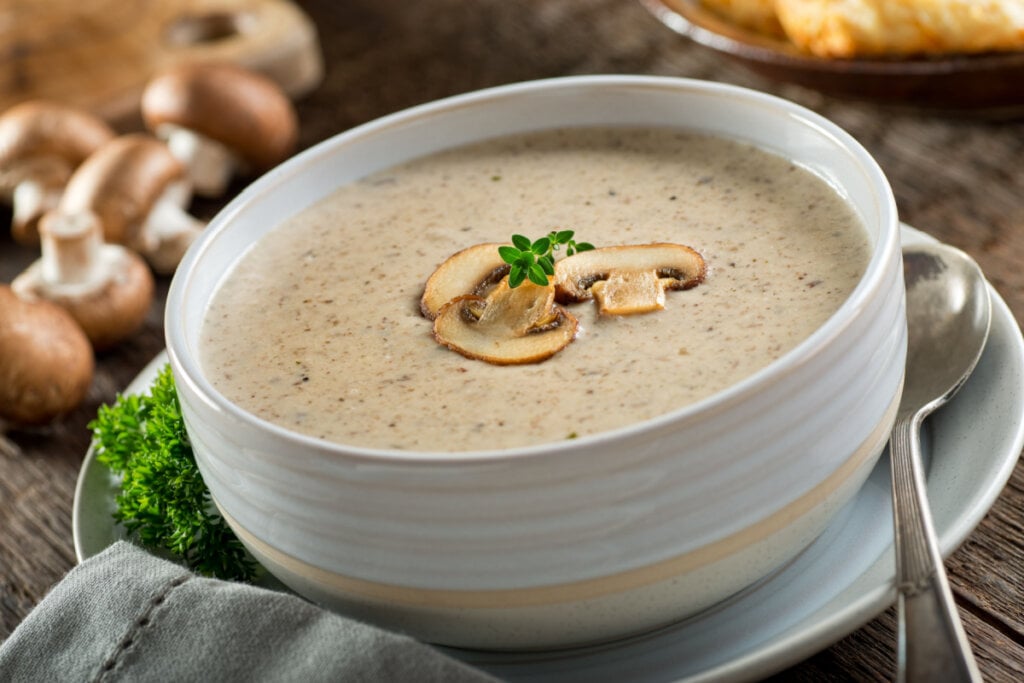 Creme de cogumelo em recipiente branco com colher ao lado