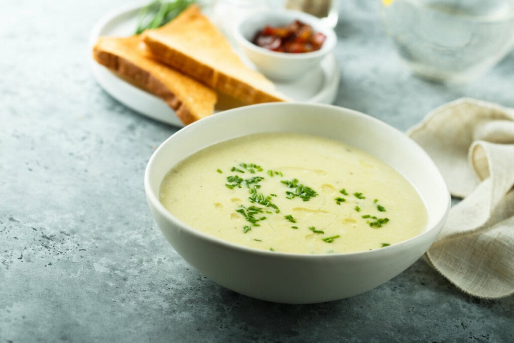 Recipiente branco com sopa de alho polvilhada com salsinha