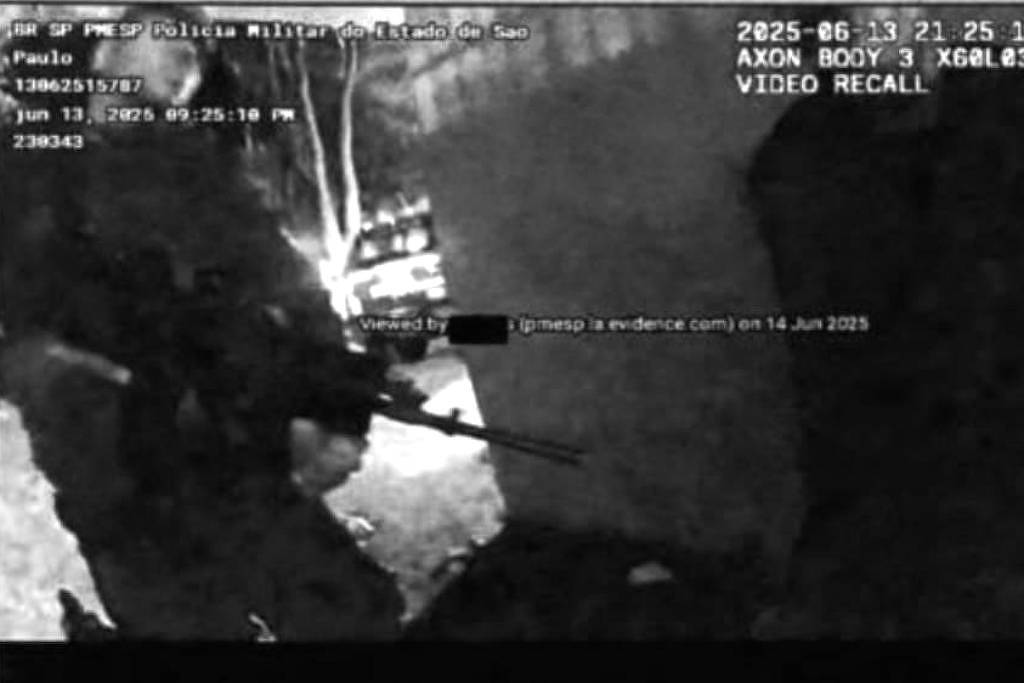 A imagem mostra uma cena de ação policial, onde um policial armado está em pé, apontando uma arma em direção a uma pessoa que está agachada ou encostada em uma parede. A iluminação é baixa, e há um veículo ao fundo. A data e hora da gravação estão visíveis no canto superior direito, indicando que foi registrada em 13 de junho de 2025.
