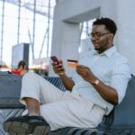 homem-segurando-celular-e-cartao-no-aeroporto