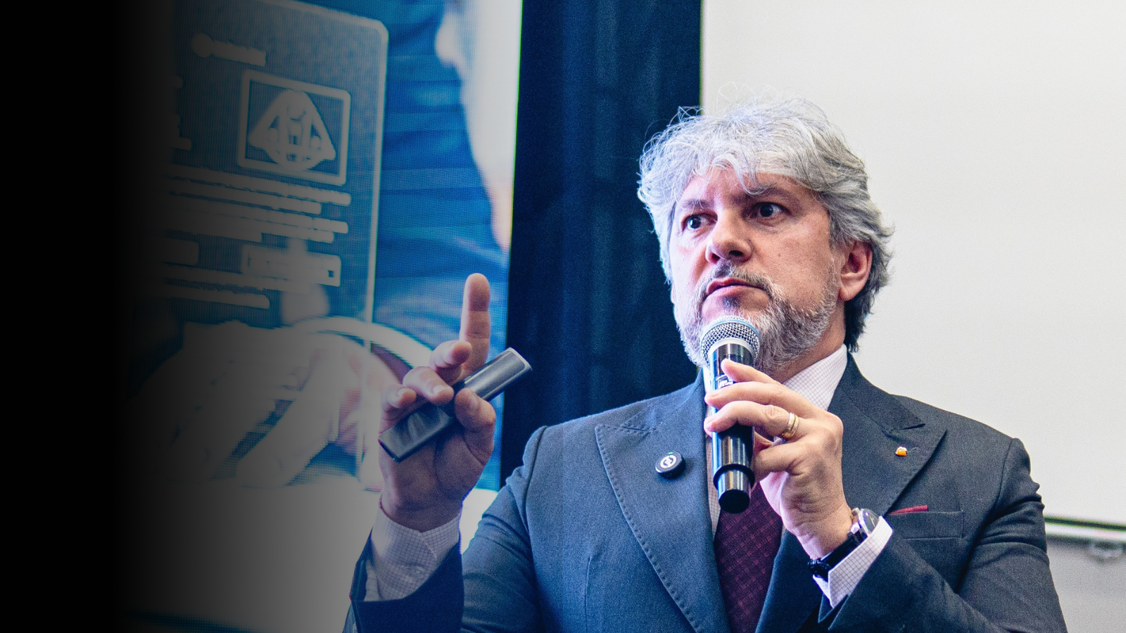 Luciano Menezes durante palestra, segurando microfone e fazendo gesto técnico, em ambiente corporativo, abordando estratégia fiscal e gestão empresarial.