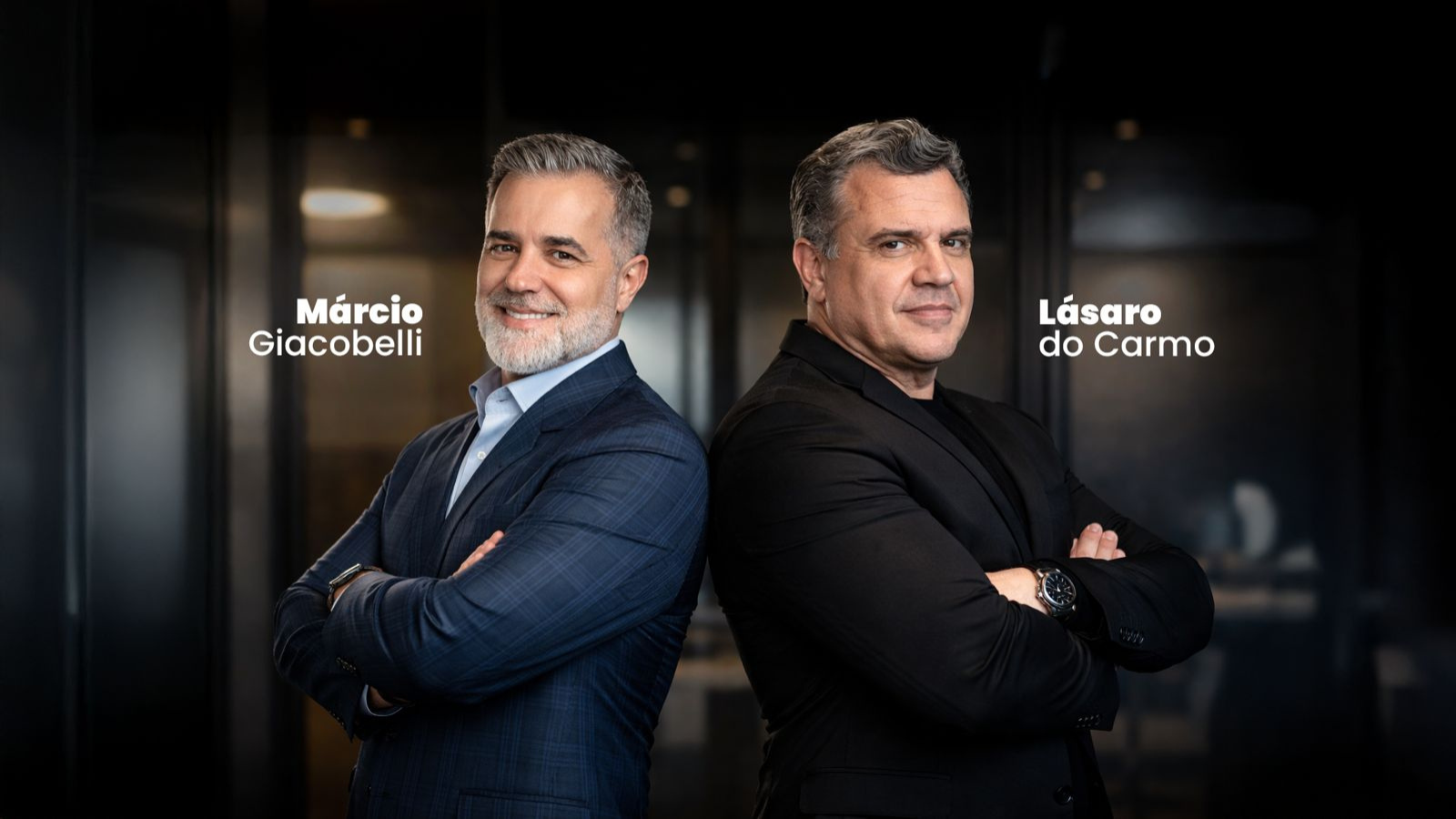 Marcio Giacobelli e Lásaro do Carmo Jr. posam lado a lado, de braços cruzados, em ambiente corporativo, representando liderança e tomada de decisão estratégica