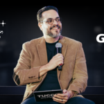 Apresentador do programa Poder & Negócios em estúdio, segurando microfone, com identidade visual do programa à esquerda e logotipo da TV Gazeta à direita em fundo escuro