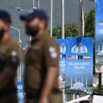 Cartazes azuis com bandeiras dos Estados Unidos, Paquistão e Afeganistão anunciam as