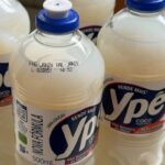 Cinco garrafas transparentes de detergente líquido Ypê coco, com tampa azul, dispostas em superfície clara. Rótulos exibem marca, volume de 500 ml e informações de fabricação.