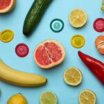 Conceito de sexo com frutas e preservativos em fundo azul