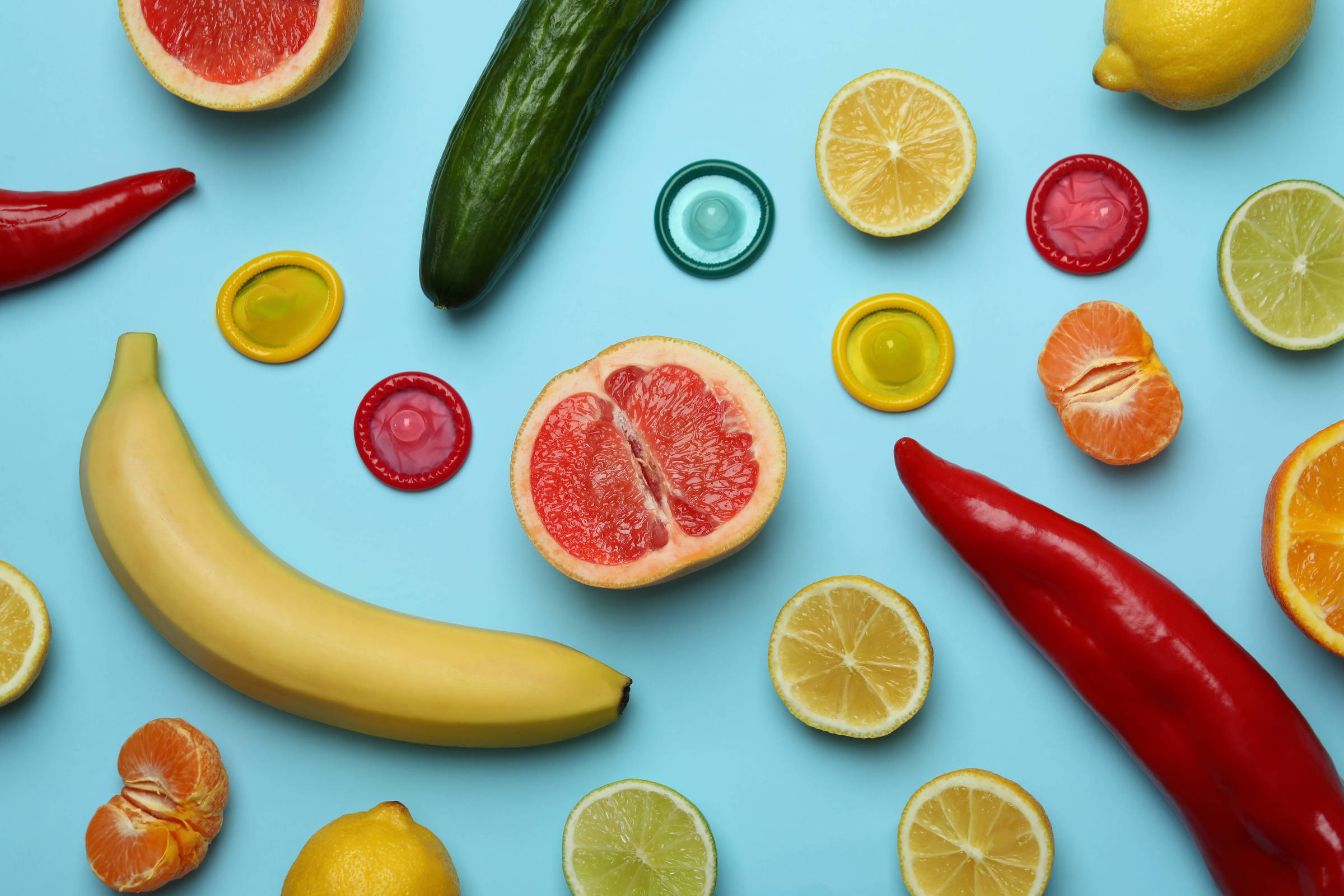Conceito de sexo com frutas e preservativos em fundo azul