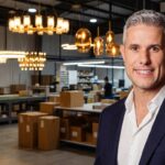 Eduardo Vaccari em fábrica de lustres com operação de produção e logística ao fundo.
